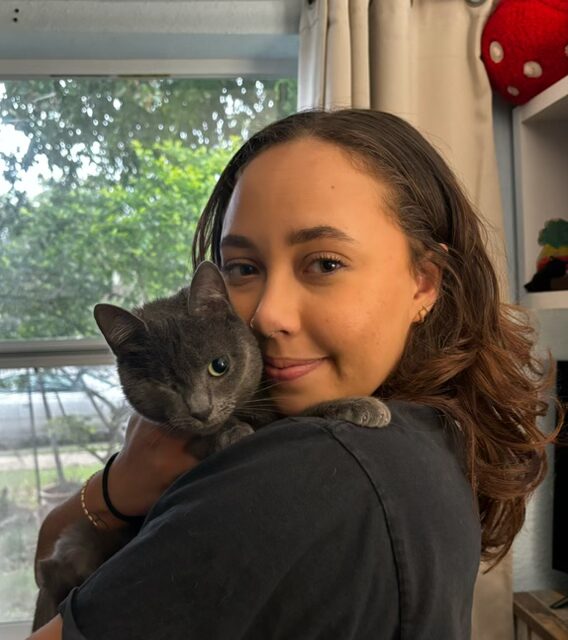 Woman holding gray cat indoors near window at Fort Lauderdale Veterinary Center
